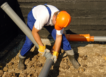Image of a person working on a drainage pipe.